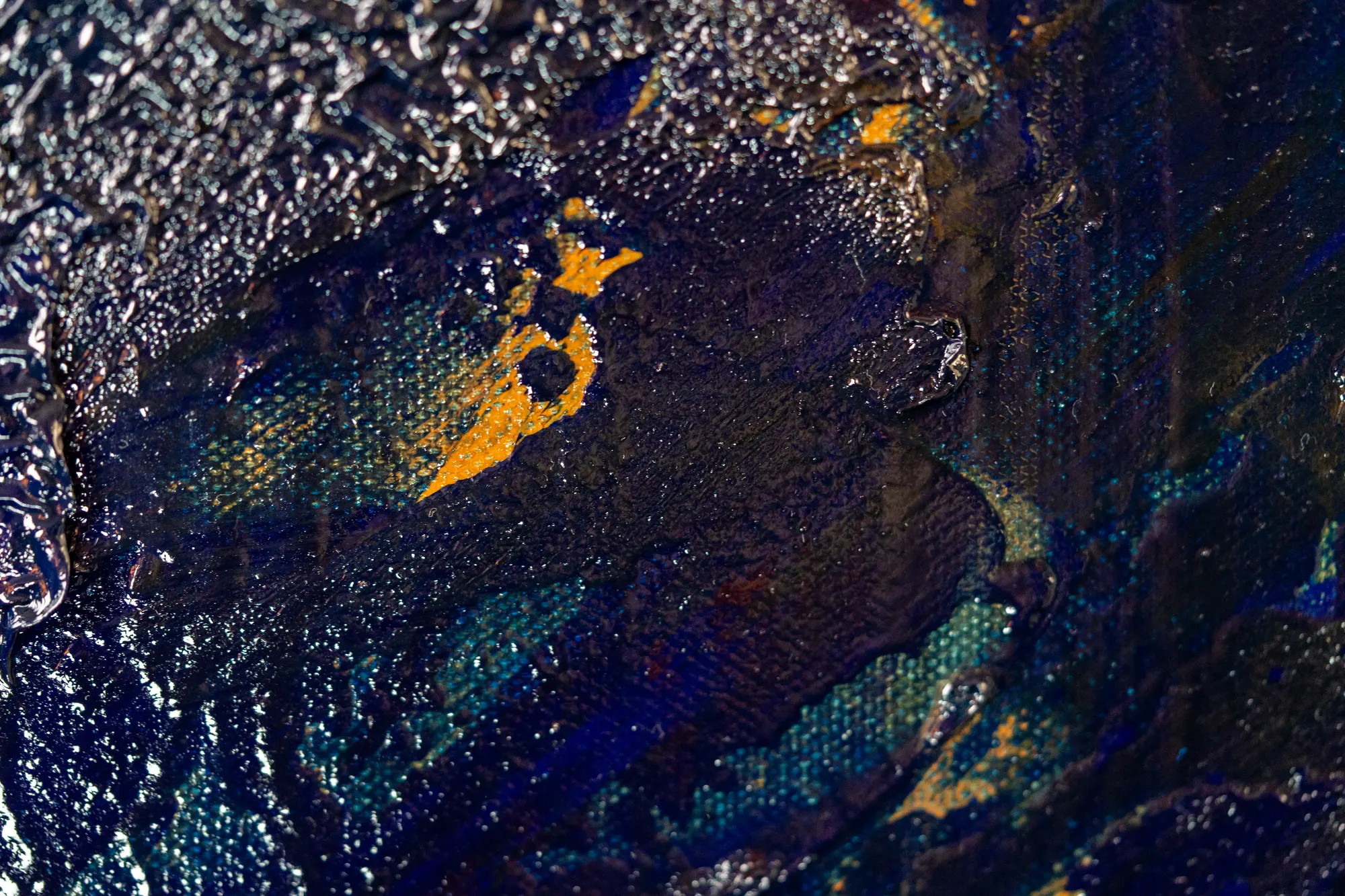 Close view of a single orange mark surrounded by dark blue and a rim of pitted silver crust.
