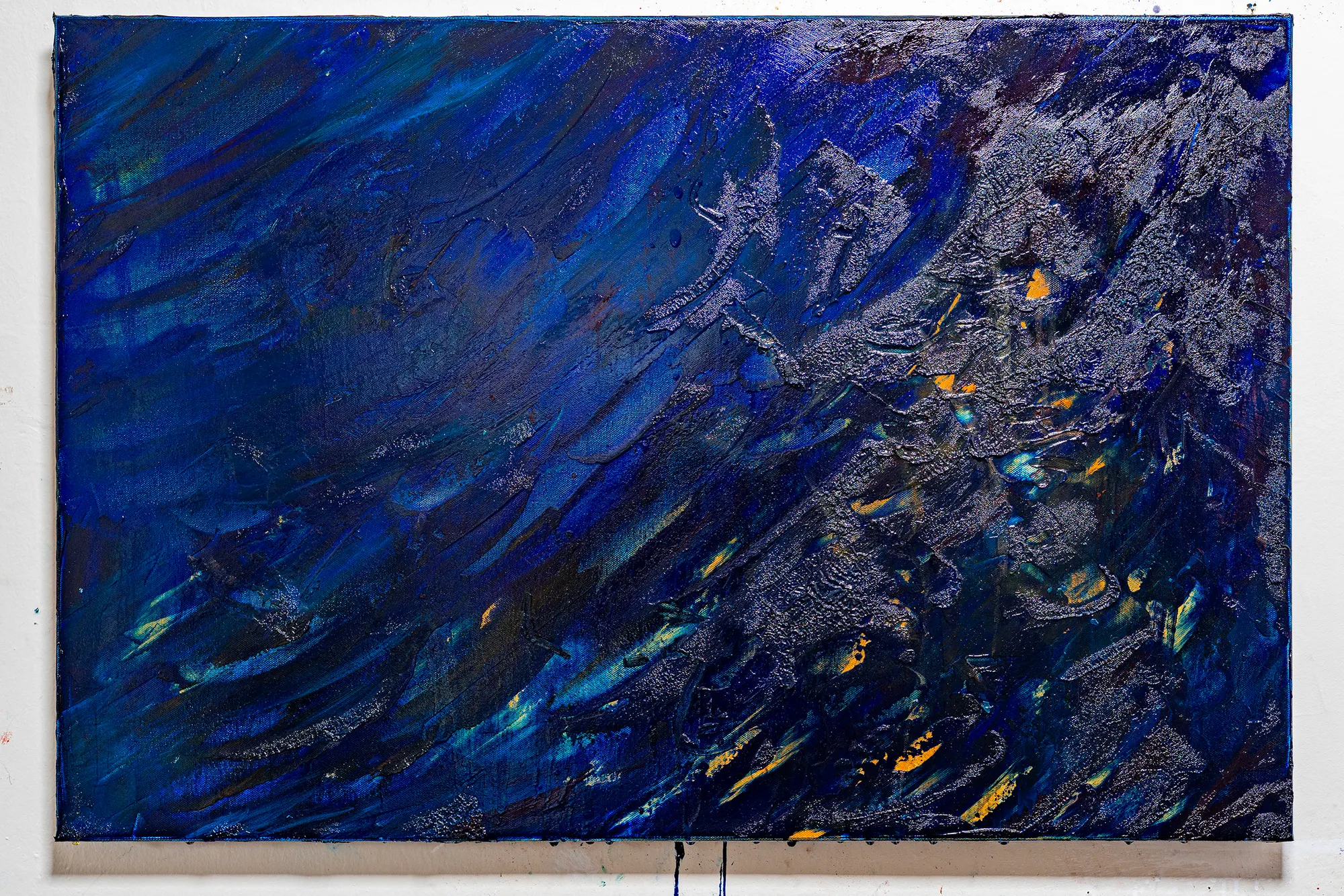 Blue #1: a deep blue field crossed by a diagonal band of crusted silver and black, small orange marks surfacing through it.