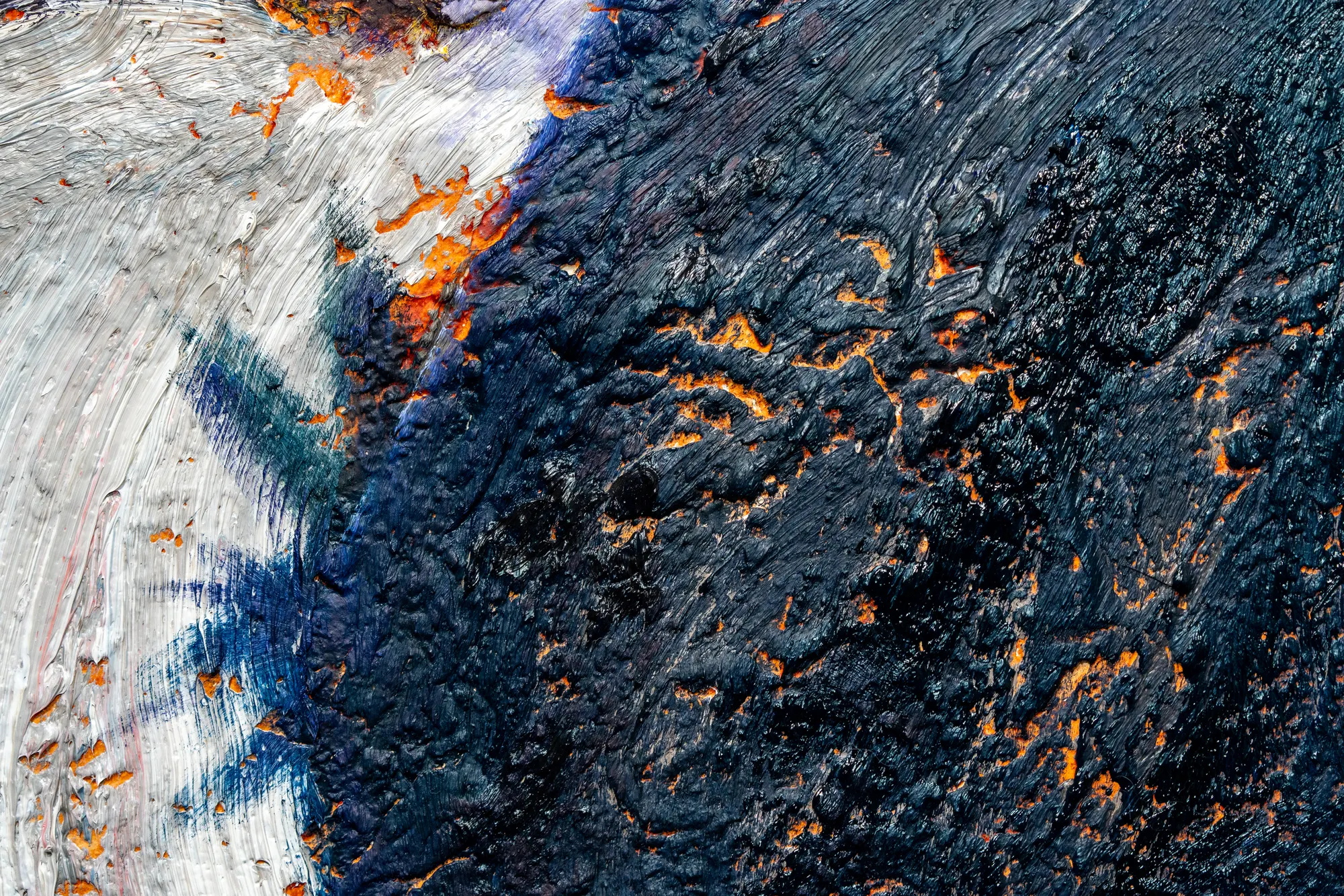Close view where smooth white paint meets a black crusted field, orange burning through every fissure.