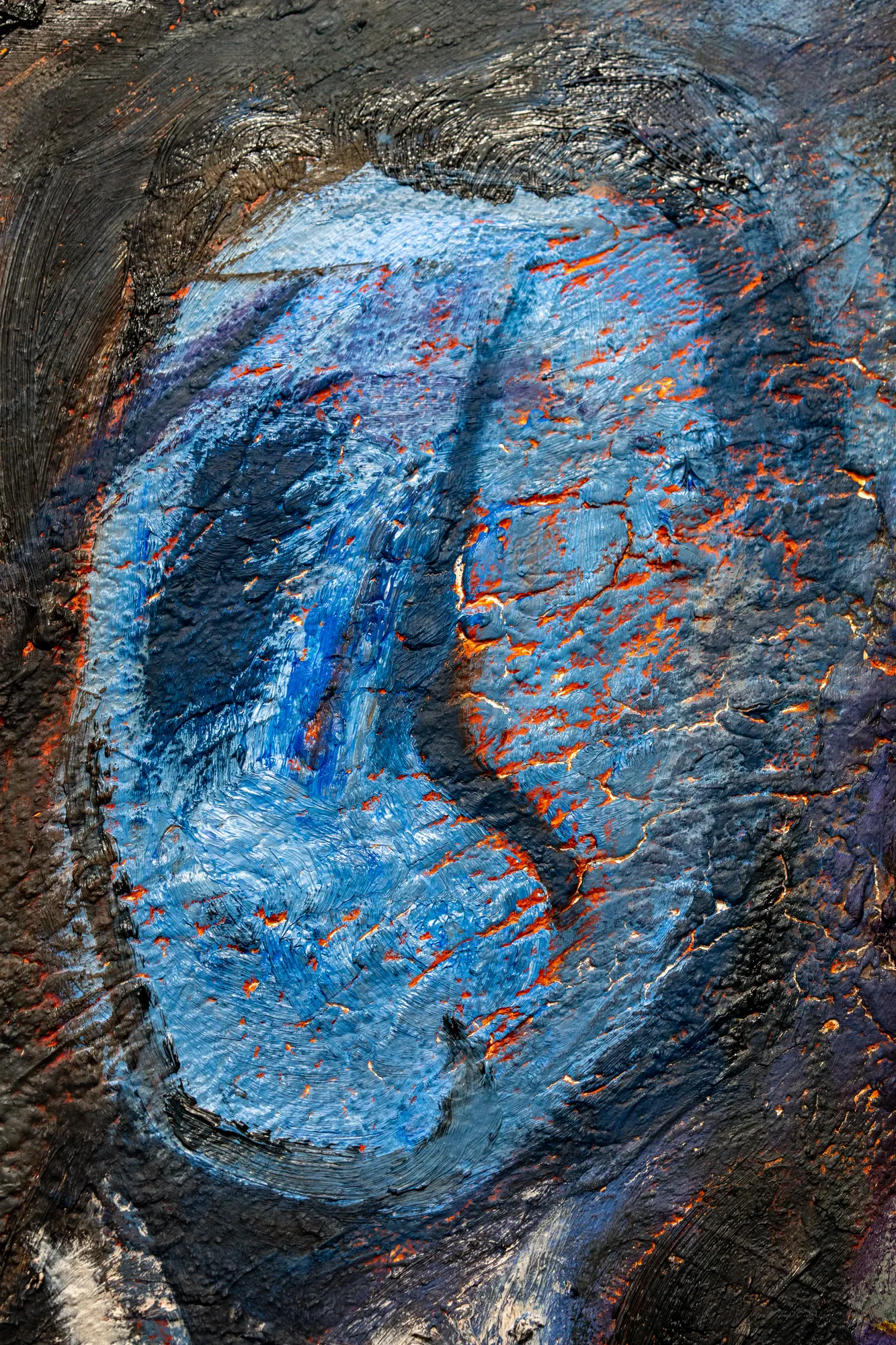 Upright close view of the blue head, orange showing through a network of cracks across its surface.