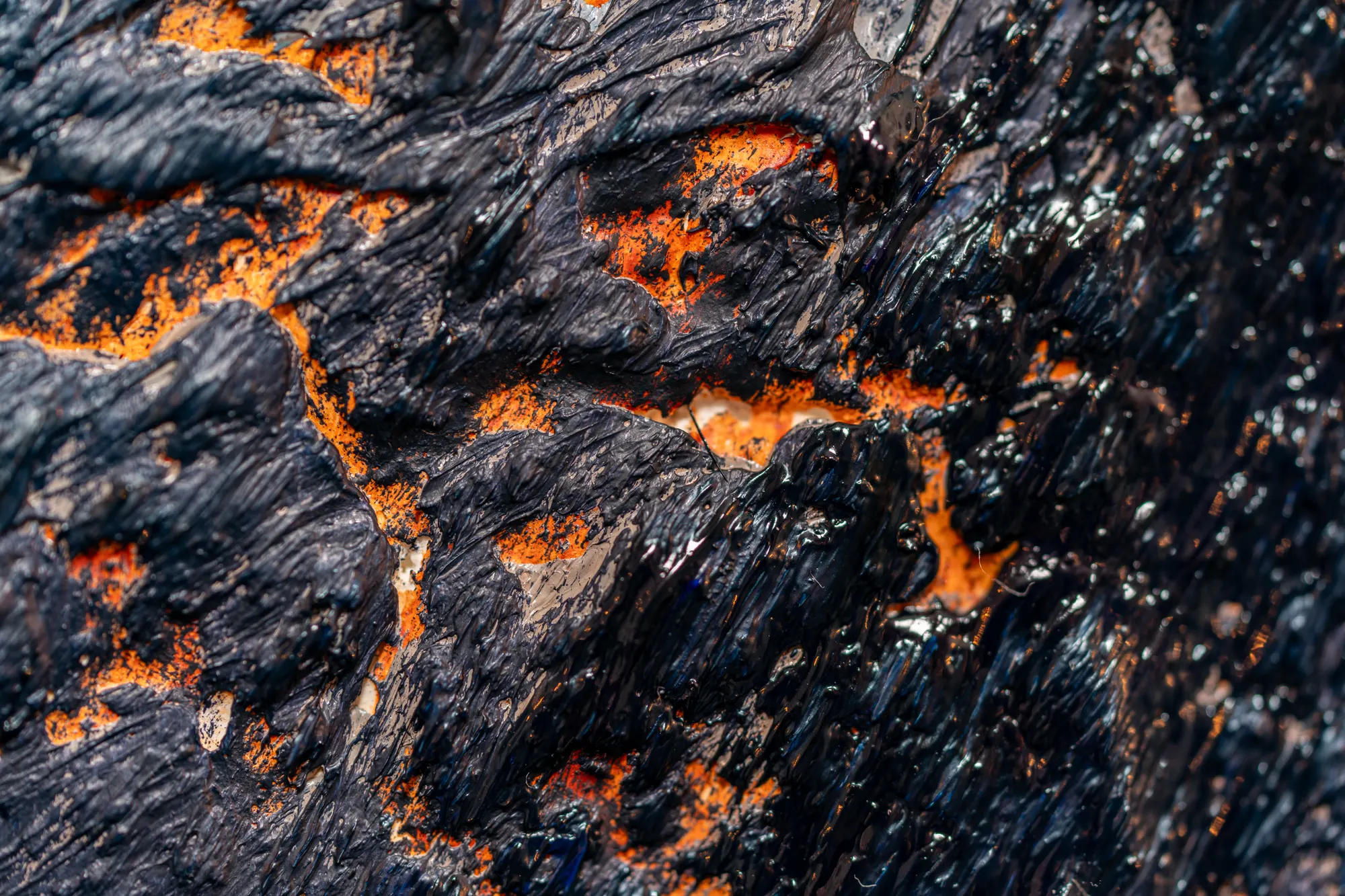 Close view of black crusted ridges with bright orange opening between them.