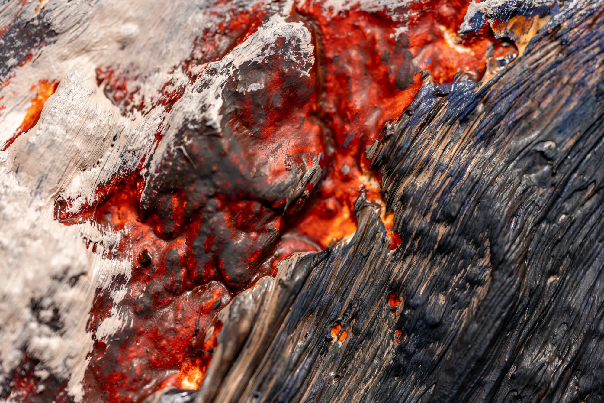 Close view where white and scarlet meet a ridge of near-black paint.