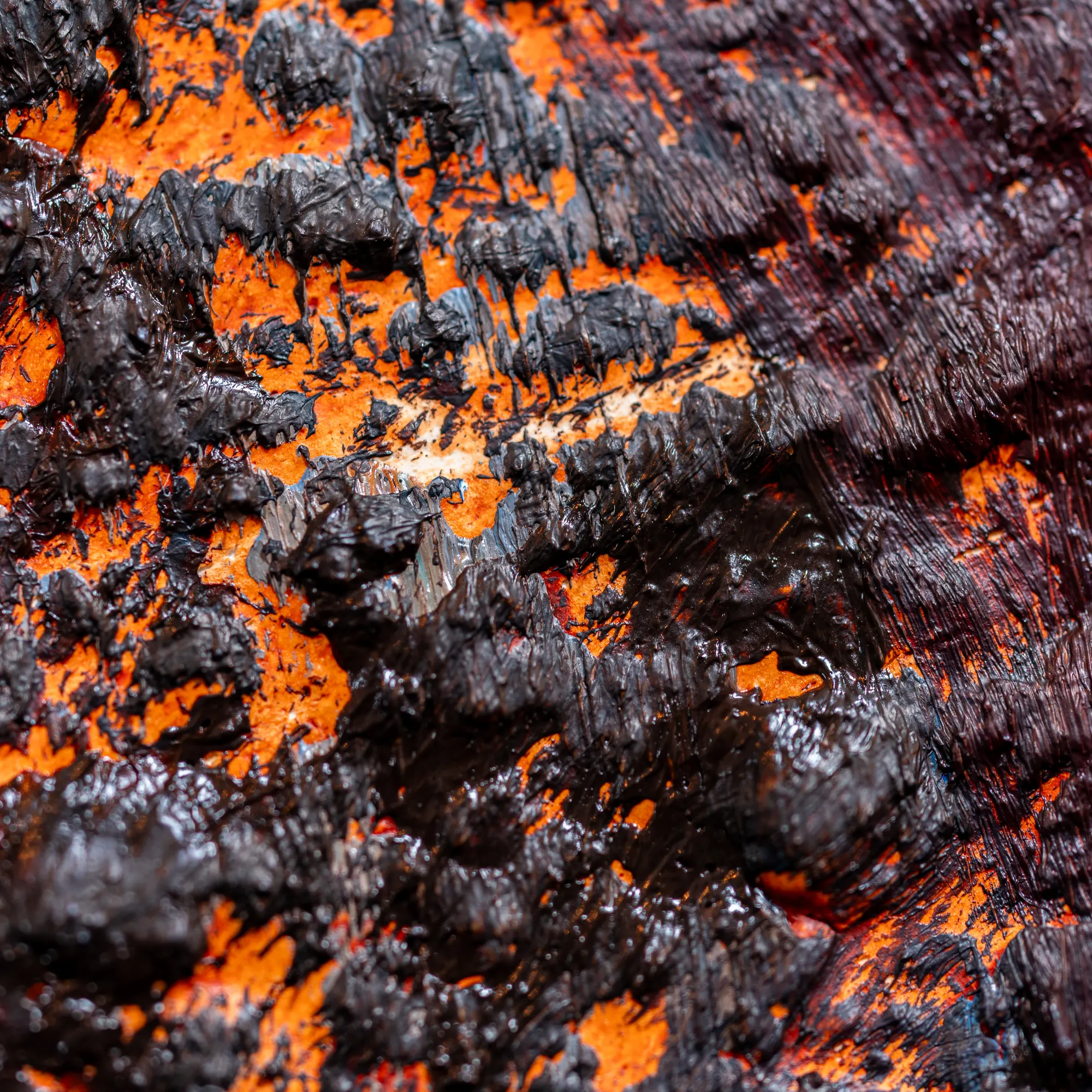 Square close view of an orange field broken up by dark glossy ridges of paint.